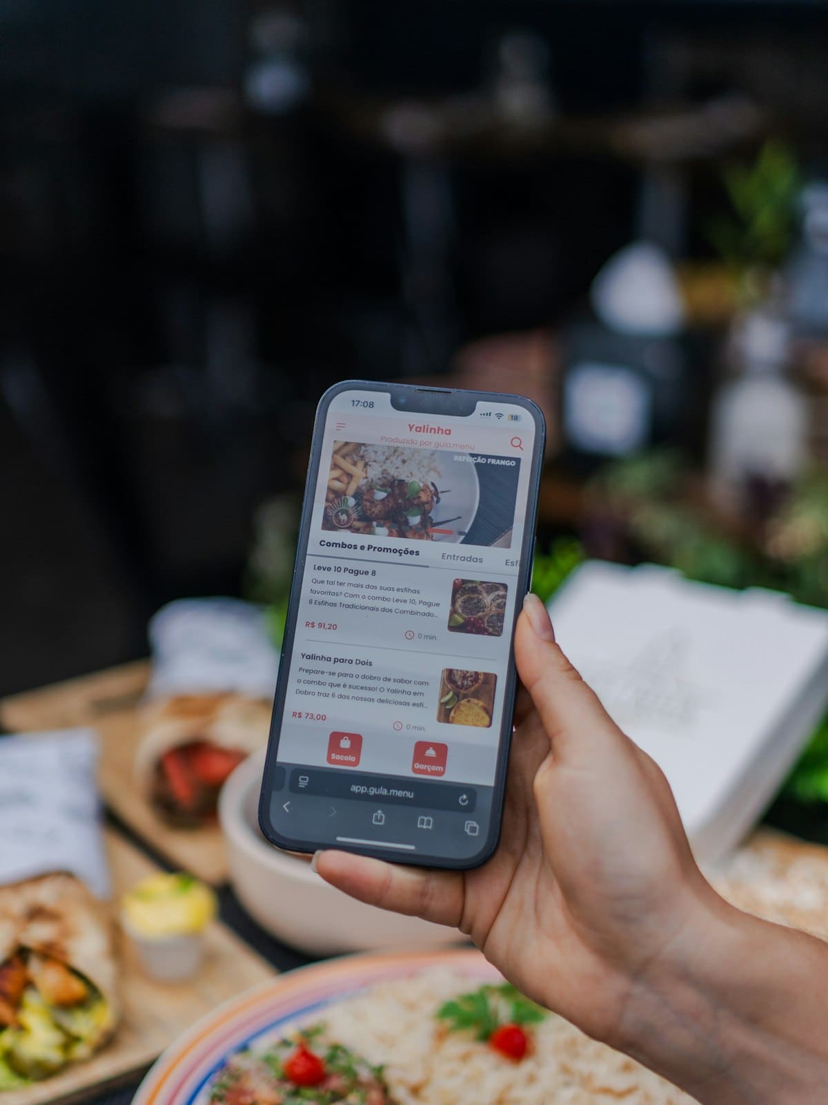 A customer browsing a restaurant menu on their phone at a table of food