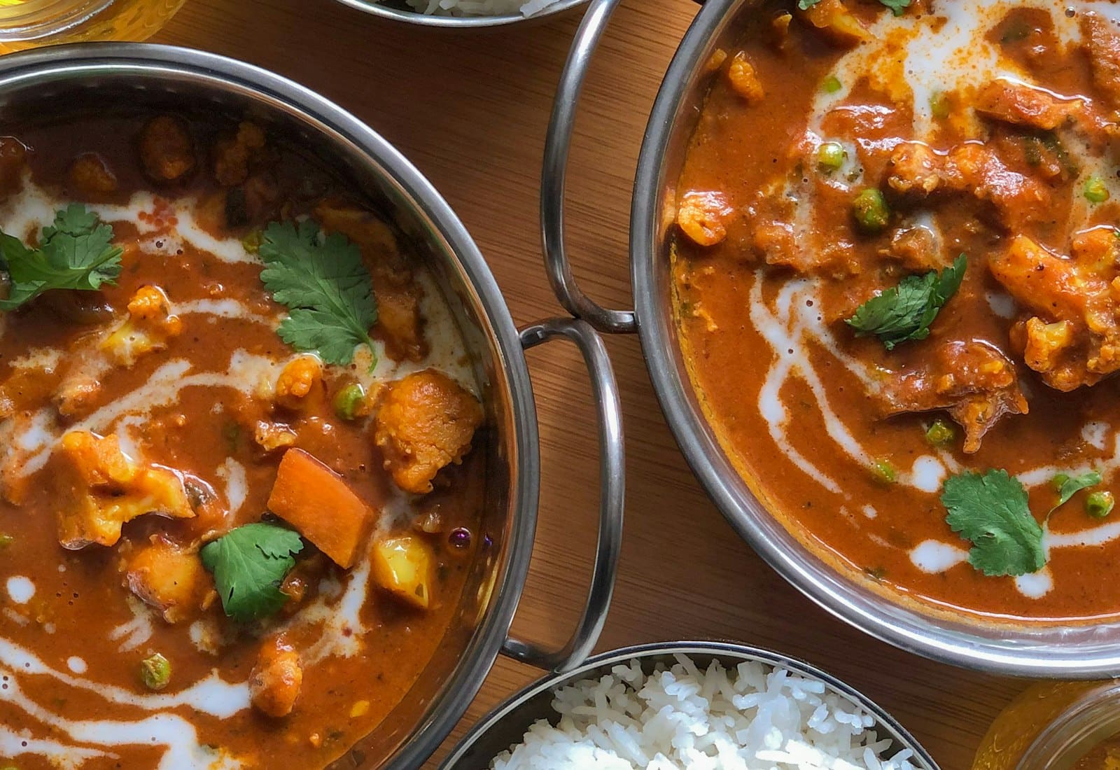 Bowls of curry and rice photographed from above on a wooden table